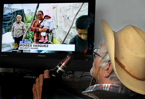 John Pint watching Al Jazeera on TV linked to computer